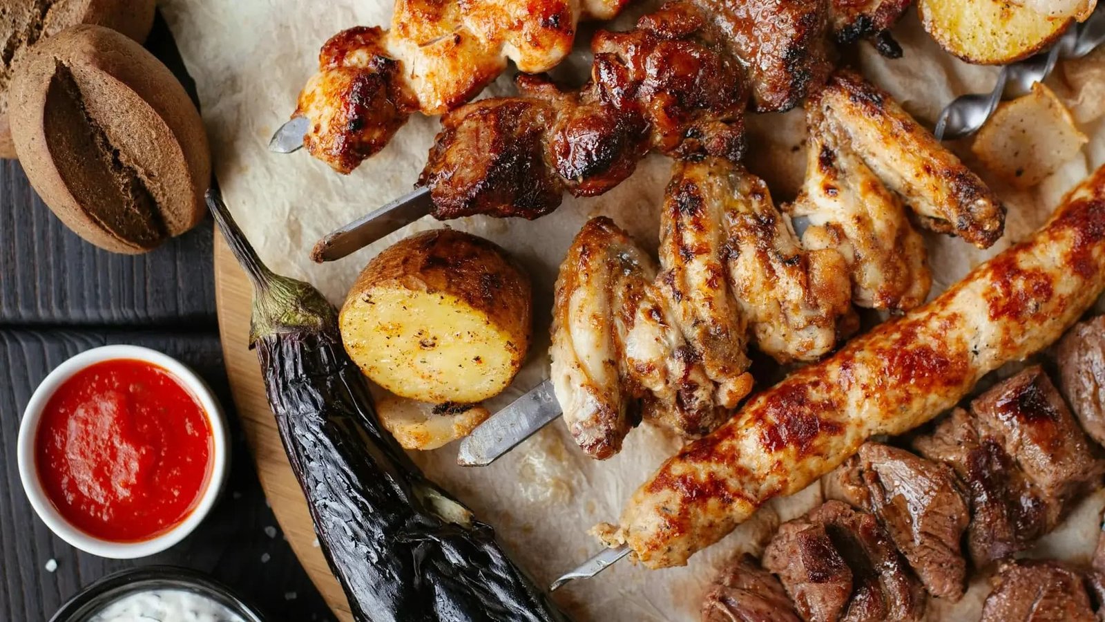 A restaurant platter of grilled meat skewers, chicken wings and roasted vegetables