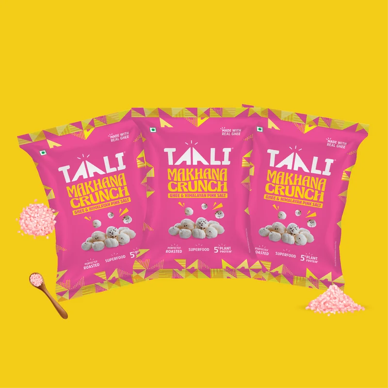 Taali Roasted Makhana Crunch Ghee and Himalayan Pink Salt 58 g packs fanned out on a flat colour tile