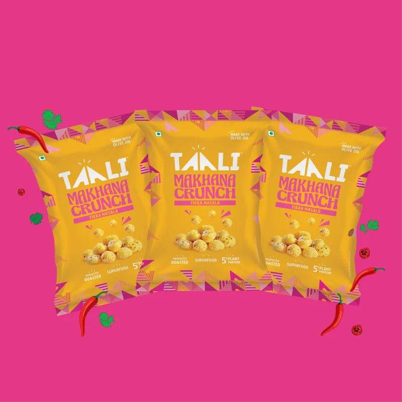 Taali Roasted Makhana Crunch Tikka Masala 60 g packs fanned out on a flat colour tile
